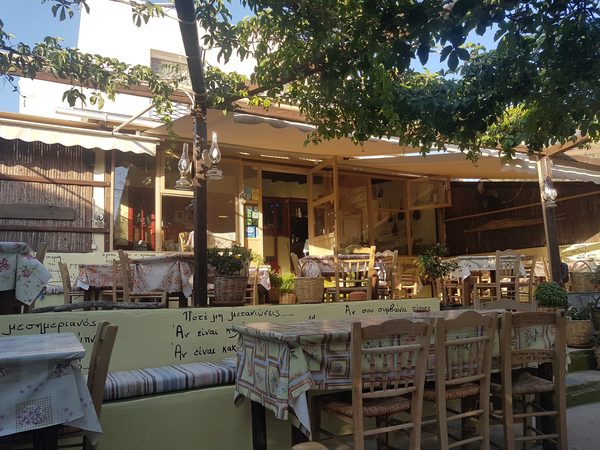 A traditional taverna courtyard near Adamas with tables set under a vine trellis in the early evening