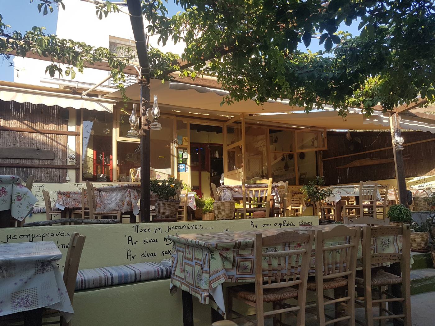 A traditional taverna courtyard near Adamas with tables set under a vine trellis in the early evening