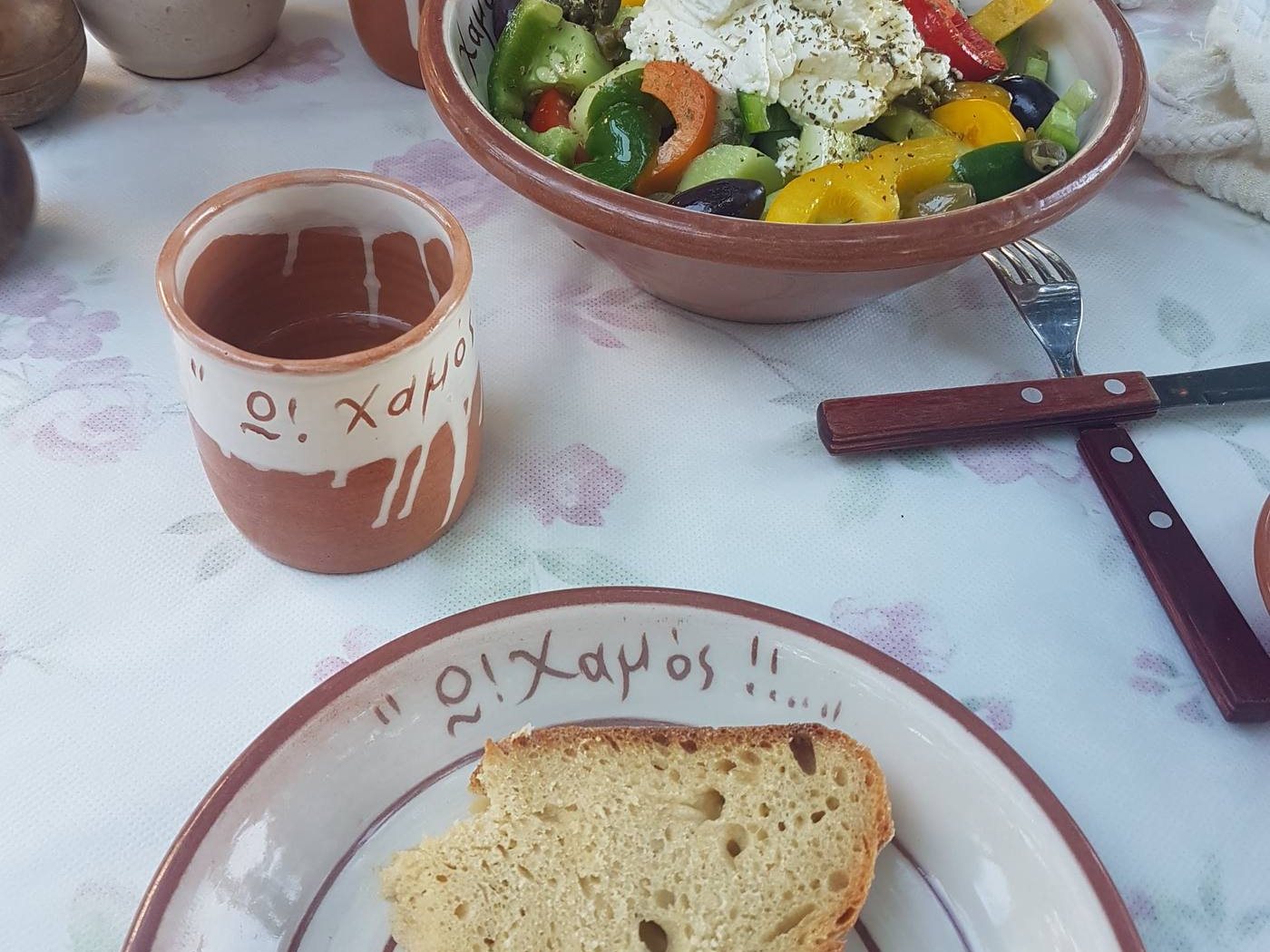 A Greek salad with feta, peppers, olives and capers served with fresh bread at a Milos taverna
