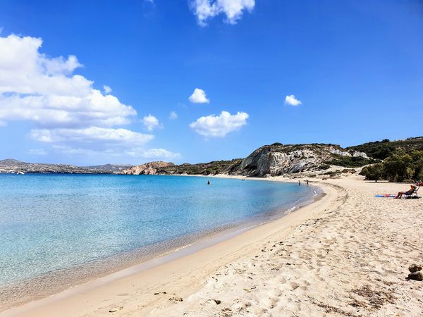 The long curving bay at Firiplaka beach, with pale cliffs rising above clear turquoise water and a wide sandy shore