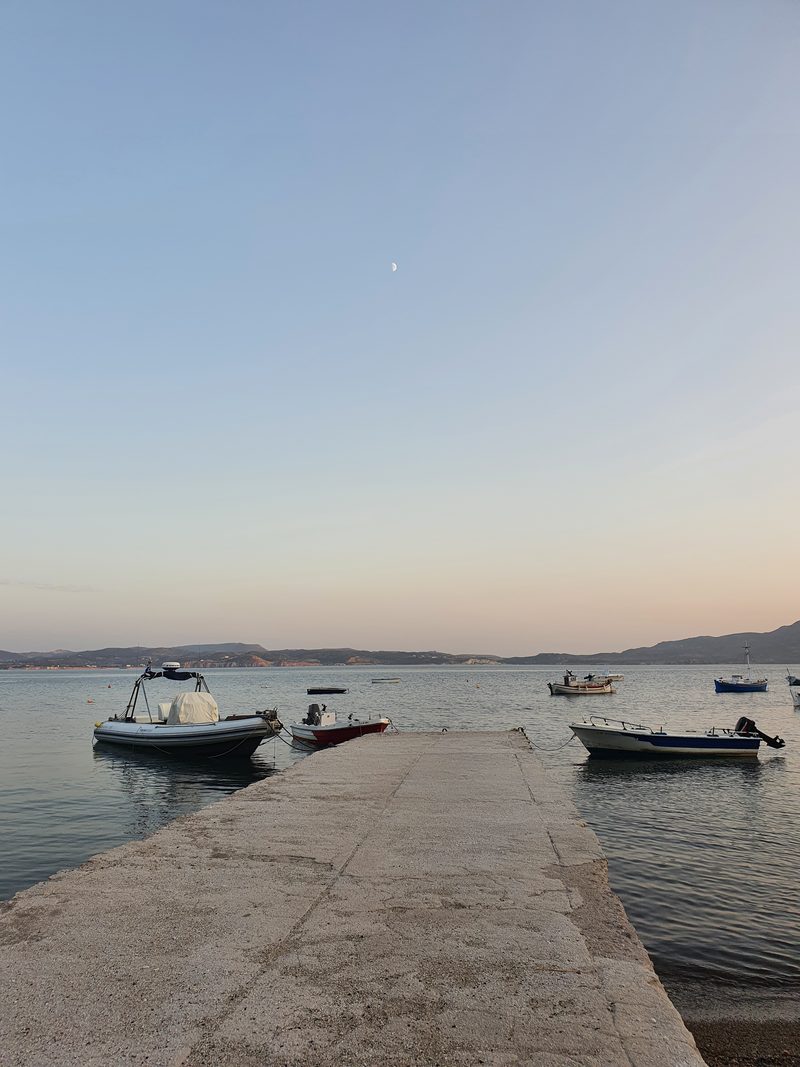 Small boats moored along a breakwater in Adamas harbour at dusk