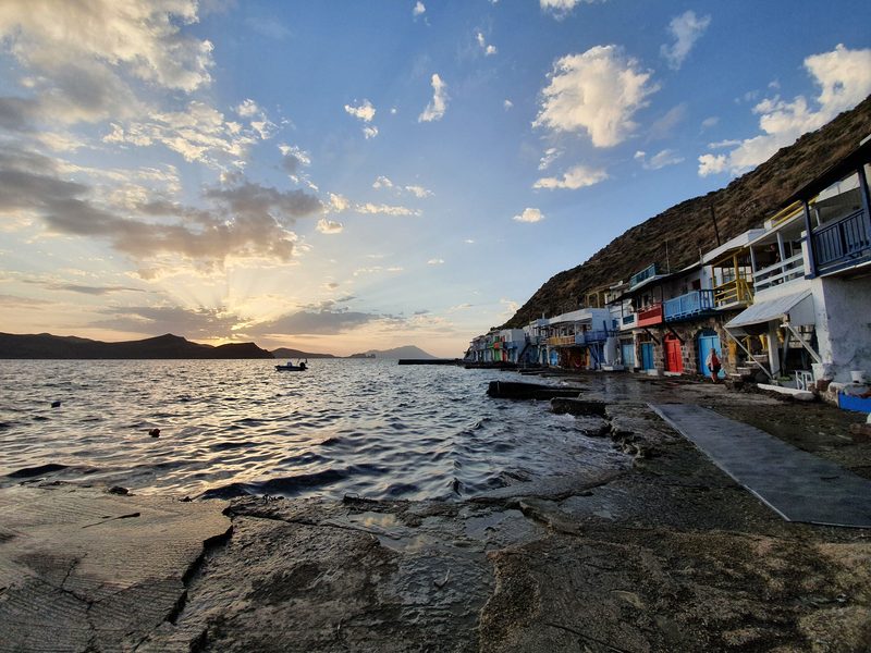 The painted syrmata boathouses of Klima lit by low evening sun, their coloured doors and balconies facing the sea