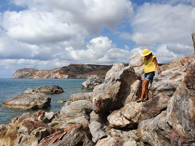 Climbing over the striped red and grey boulders on the rocky headland at the edge of Paleochori beach
