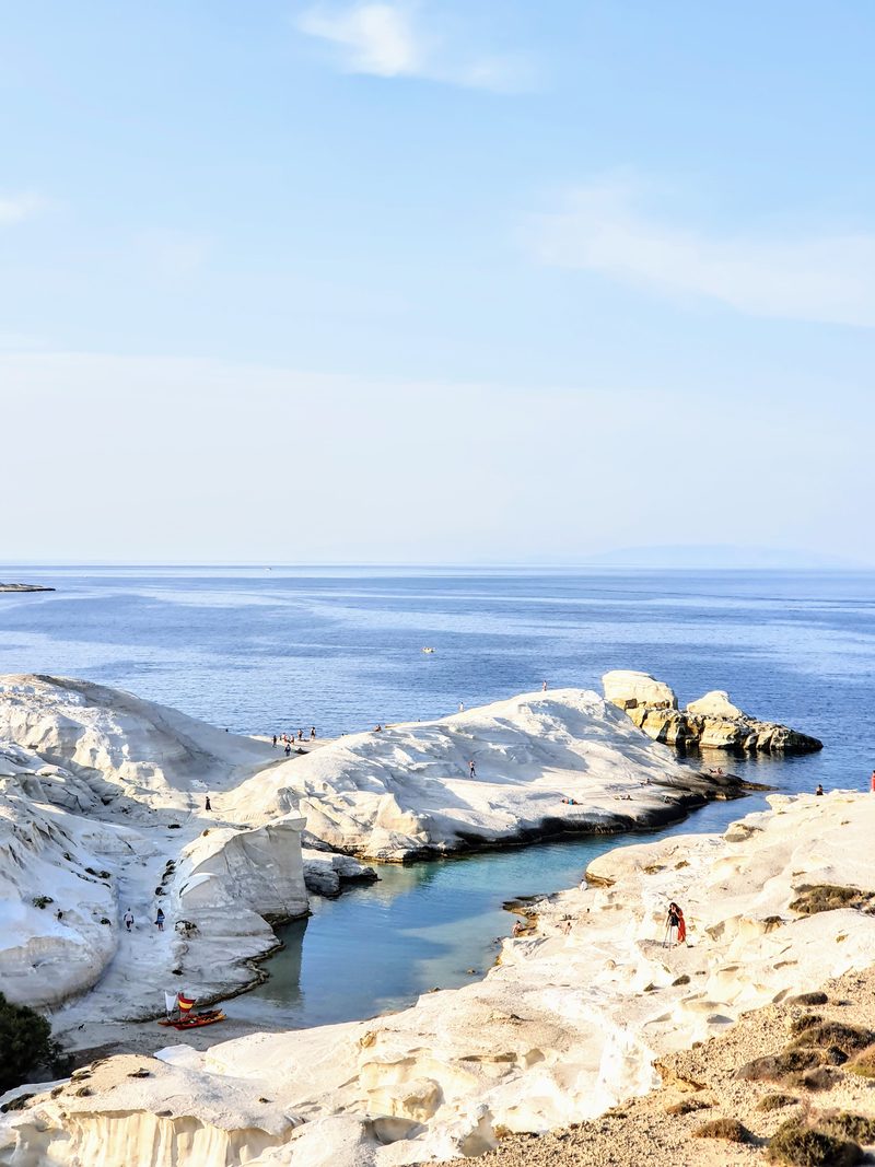 The white lunar rock formations of Sarakiniko with a narrow inlet of blue-green water cutting into the bay