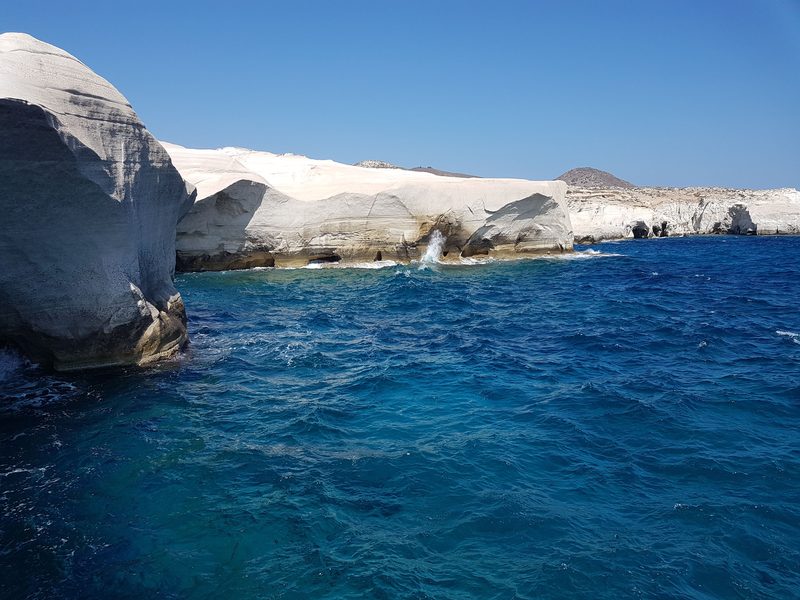 Deep blue water and sea caves at the base of the white cliffs near Sarakiniko