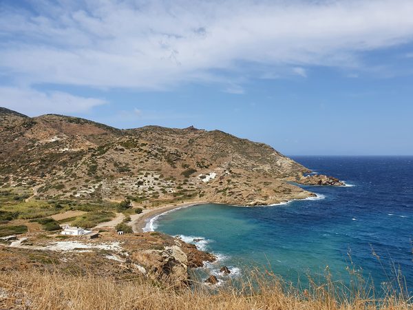 A turquoise bay with a sandy beach on the north-east coast of Kimolos, seen from the coastal path above