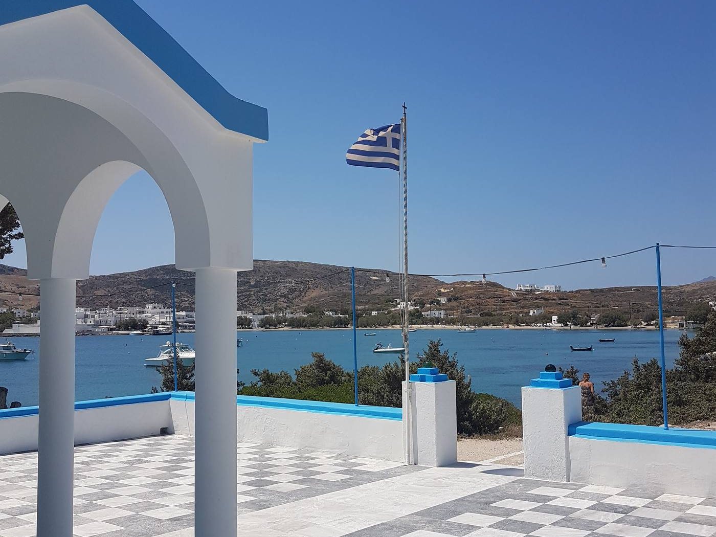 Looking down from a chapel terrace over Pollonia's harbour, beach and low white village
