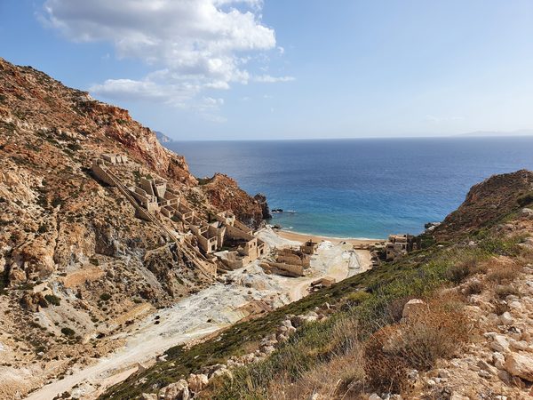 The abandoned Paliorema sulphur mine on Milos, ruined stone buildings and rusted cable lines on ochre-stained cliffs above the sea