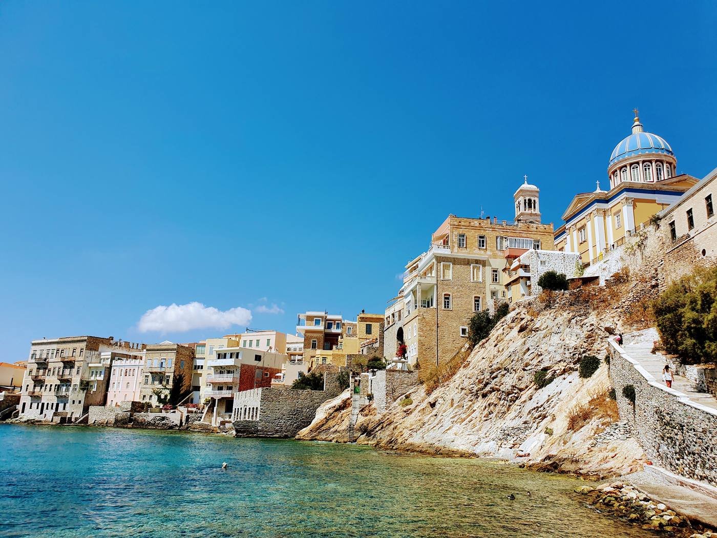 Neoclassical buildings and a blue-domed church rising above the waterfront of Ermoupoli on Syros