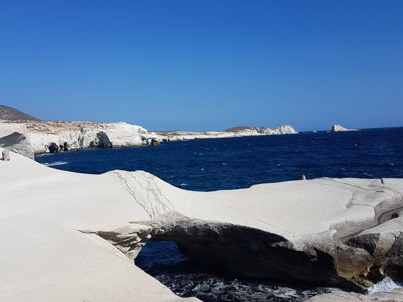 The white rock of Sarakiniko in the hard, bright light of a June afternoon, with deep blue water below