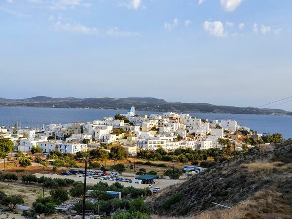 An elevated daytime view over the whitewashed hilltop village of Plaka and Trypiti above the bay of Milos